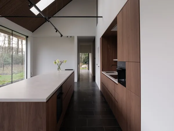 Keuken met wit geschilderde wanden en een schuin plafond naast houten maatkasten