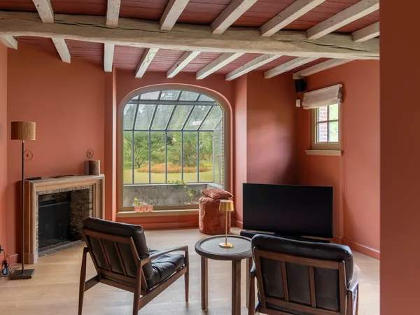 Zithoek met terracotta wanden en plafond en een wit afgewerkt balkenplafond